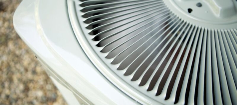 top view of fan spinning inside ac unit installed outside with protective vents